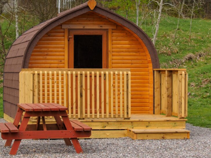 Small barrel-shaped wooden glamping pod with a porch